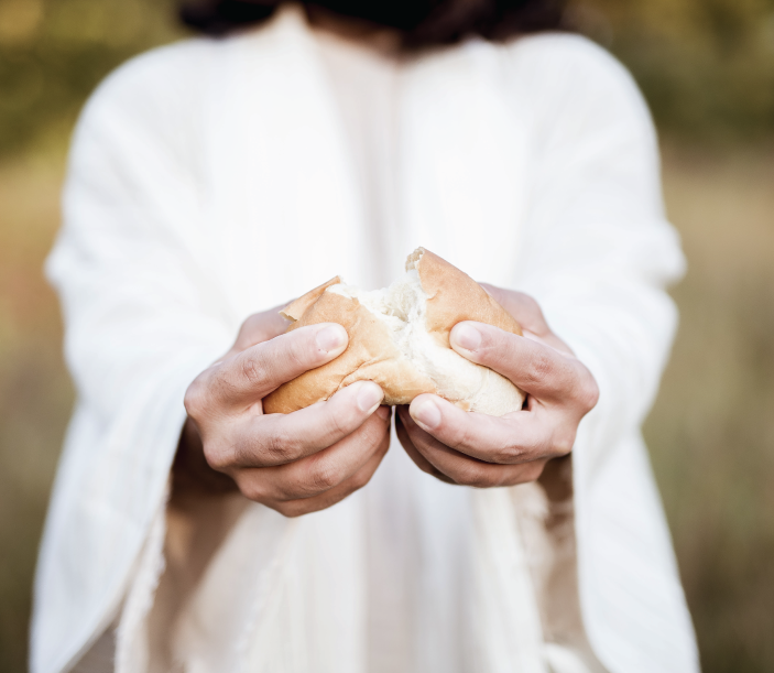 Representación de Jesús partiendo un pan y ofreciéndolo.
